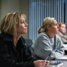 A woman looking attentively ahead in a classroom.